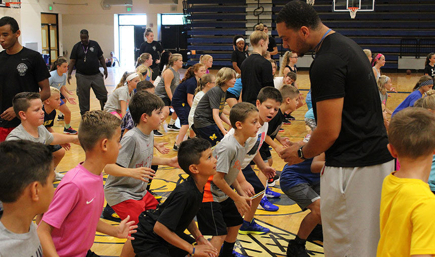 Coaches helping basketball campers work on defense skills